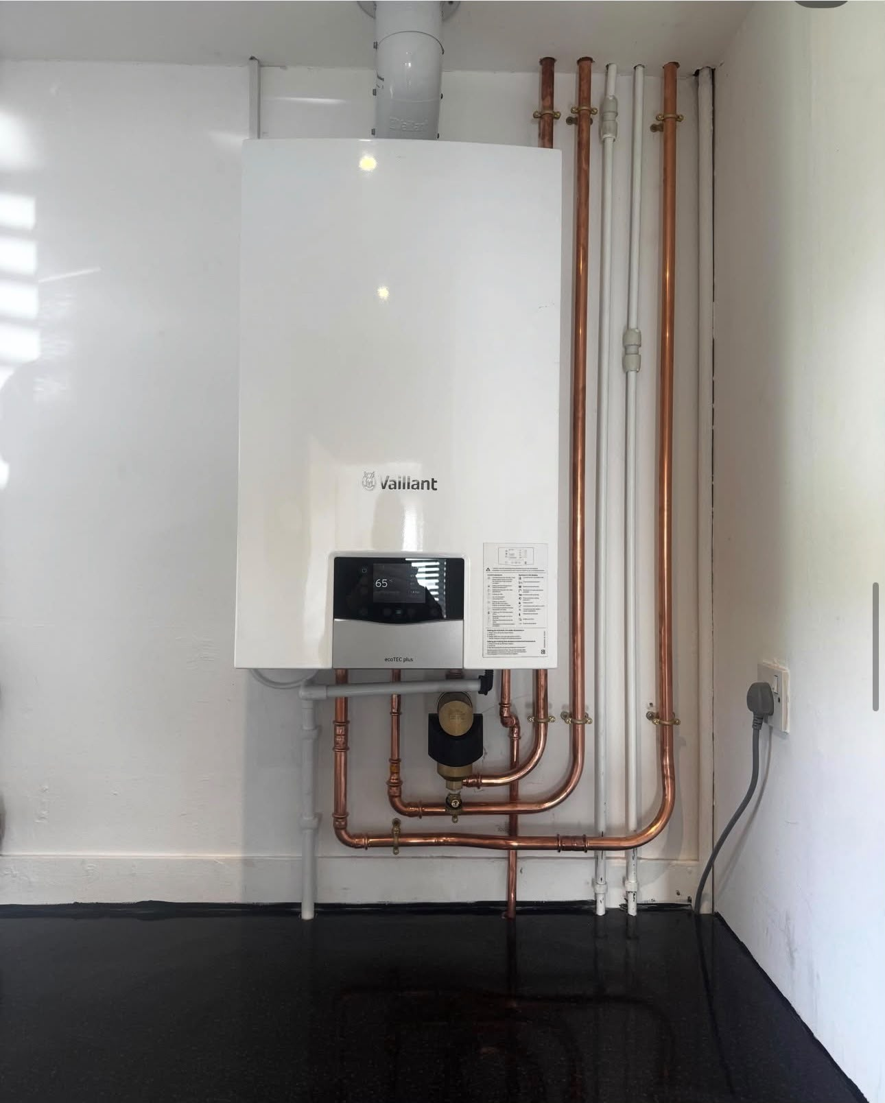 New Vaillant boiler installation with exposed copper pipework and clean wall finish