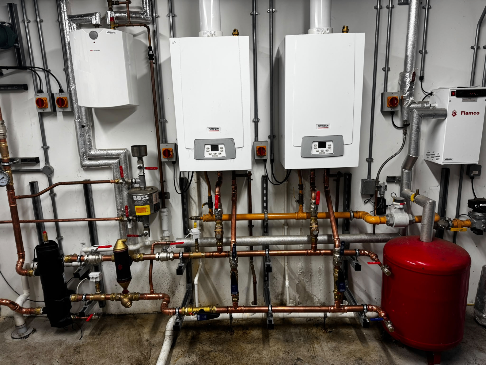 Commercial cascade boiler installation with twin wall-mounted units and extensive plant room pipework
