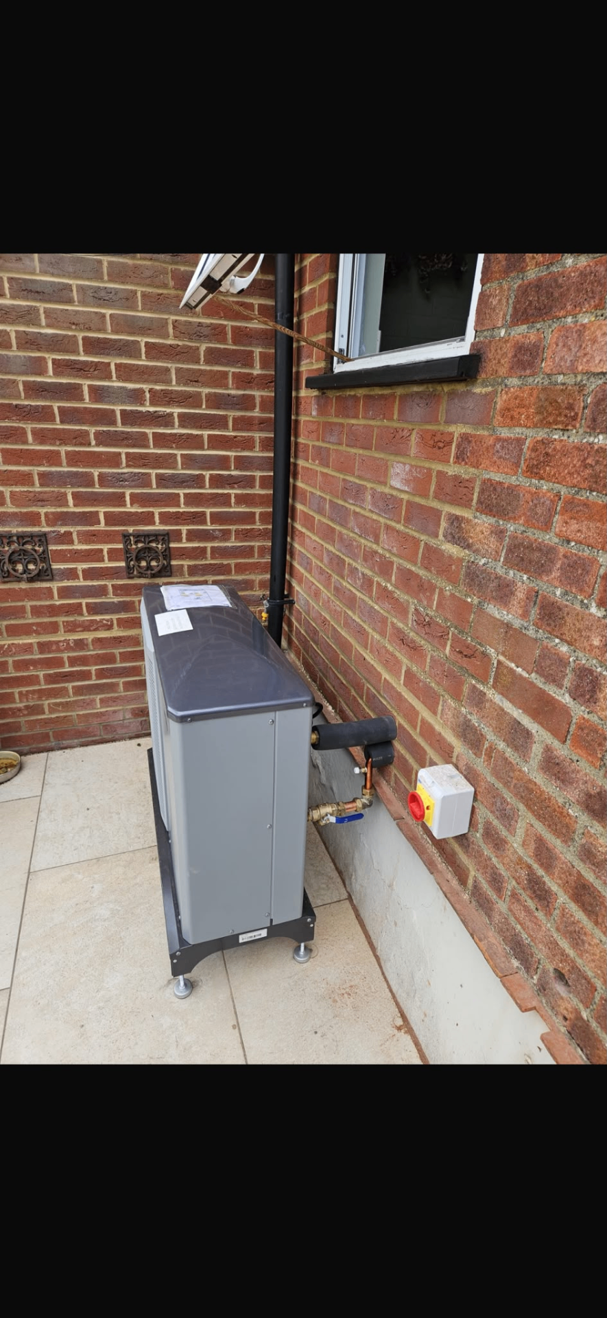 External heating unit installed neatly beside a brick wall with isolated service connections