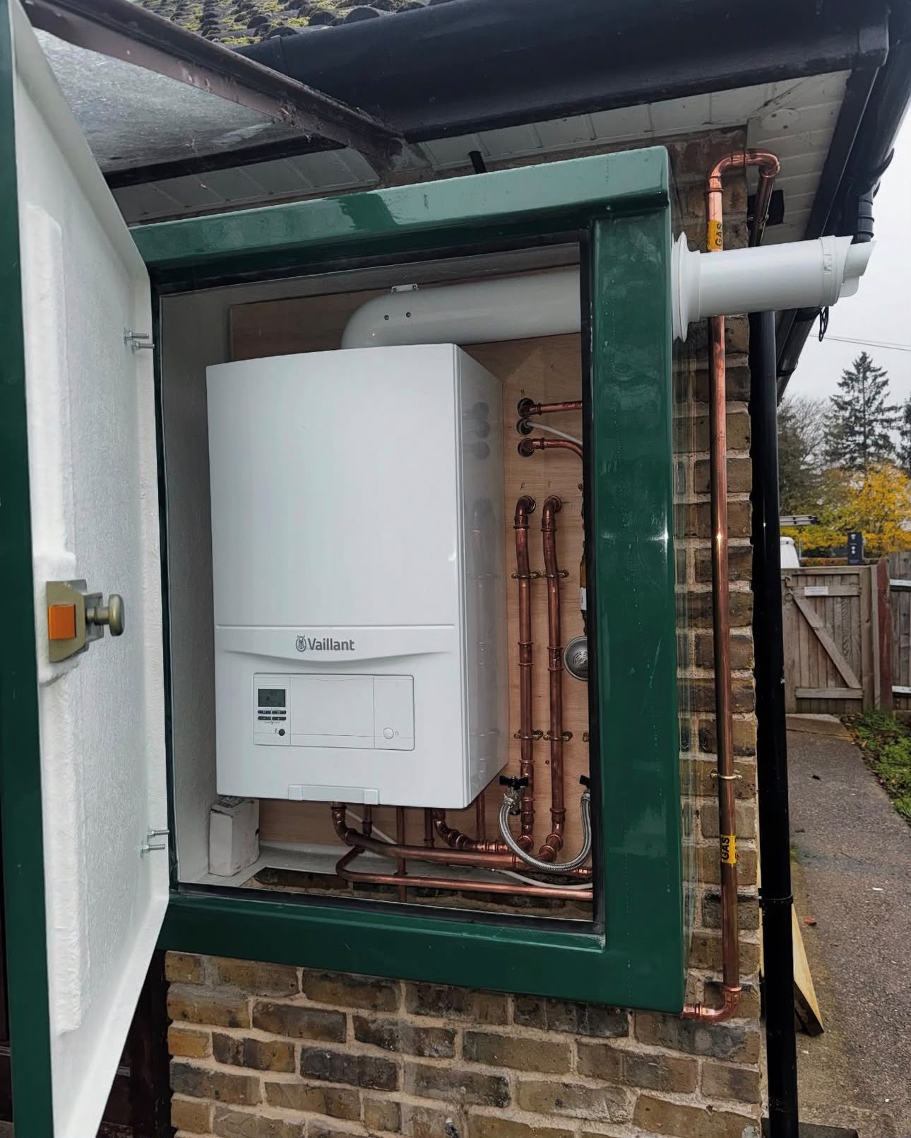 Outdoor Vaillant boiler cabinet installation with exposed copper pipework and balanced flue