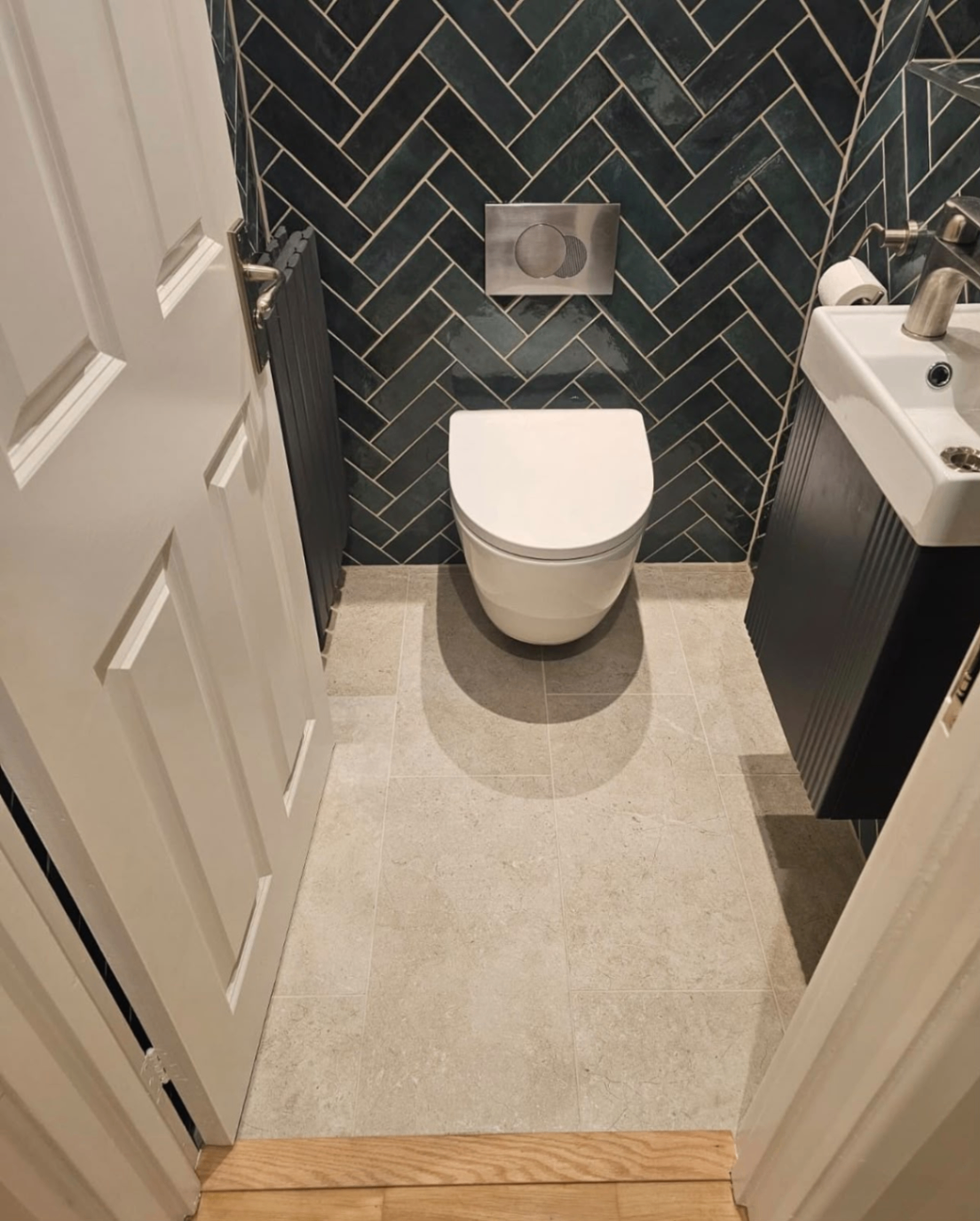 Finished cloakroom installation with herringbone wall tiles and wall-hung toilet